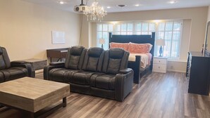 A modern living room with a leather sofa, a wooden coffee table, and a bed with a headboard. - Reserved Luxury (Lubbock)