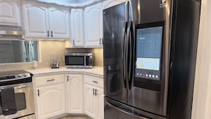A modern kitchen with white cabinetry, a stainless steel refrigerator, a microwave, and an oven. - Reserved Luxury (Lubbock)