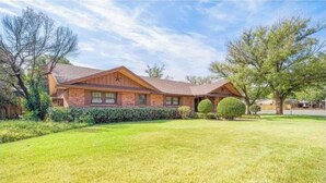 A two-story house with a brick facade, a tiled roof, and a covered patio area. - Reserved Luxury (Lubbock)