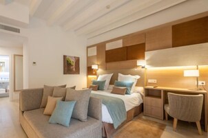 Ein modernes Hotelzimmer mit Bett, Nachttisch und einer Sitzecke mit Sofa und Sessel.