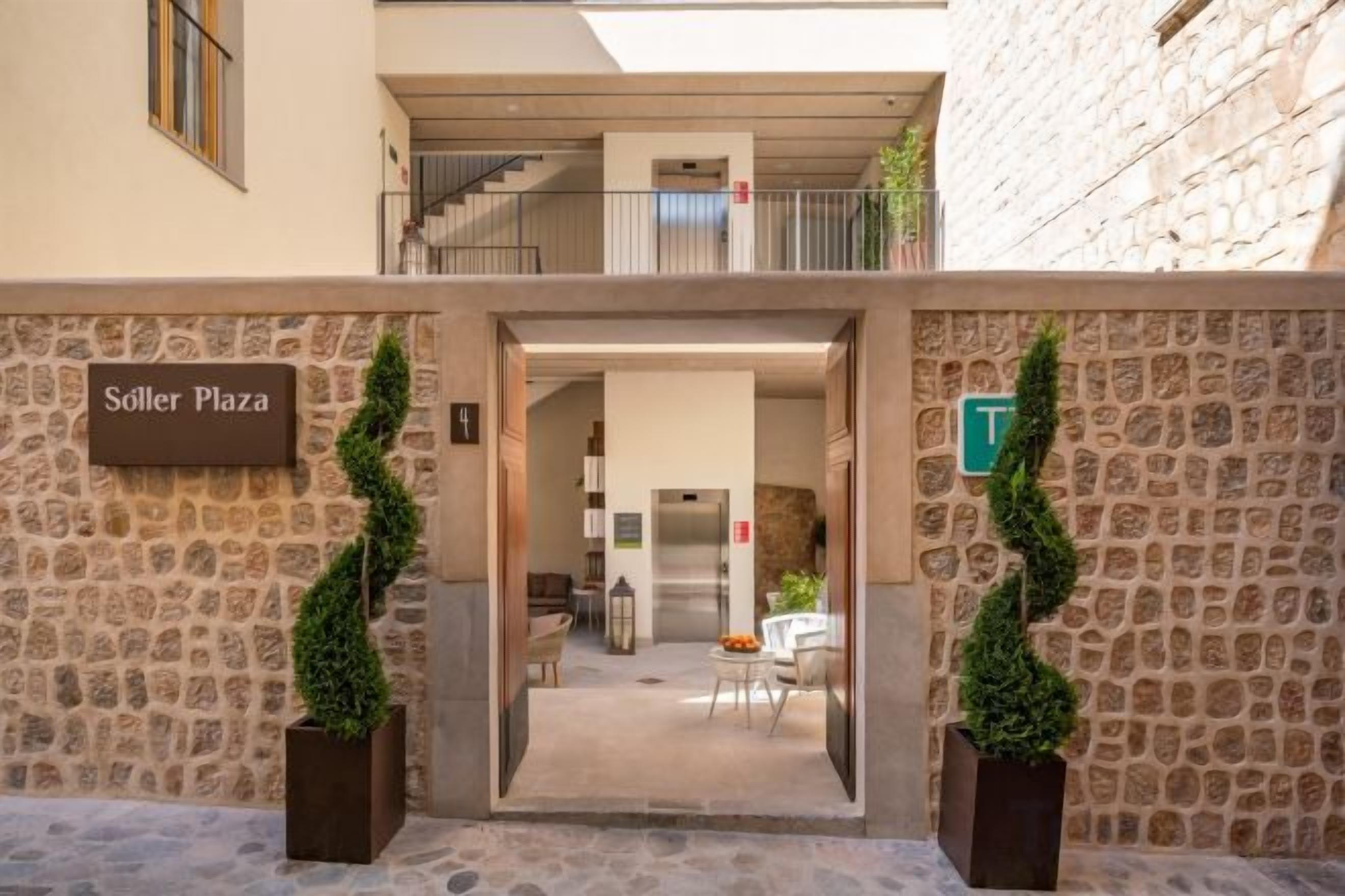 Una entrada a un hotel con fachada de piedra, un cartel que dice 'Söller Plaza' y una escalera que lleva a un nivel superior.