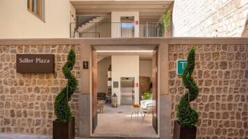 Una entrada a un hotel con fachada de piedra, un cartel que dice 'Söller Plaza' y una escalera que lleva a un nivel superior.