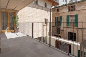Ein Balkon mit Steinmauer, Topfpflanze und Metallgeländer.