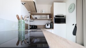 A modern kitchen with a black countertop, wooden cabinets, and a built-in oven. - Penthouse in Knokke Near Beach (Knokke-Heist)