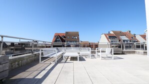 A rooftop terrace with white benches and a clear view of residential buildings in the background. - Penthouse in Knokke Near Beach (Knokke-Heist)