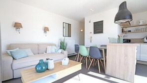 A modern living room with a sofa, coffee table, and dining area. - Penthouse in Knokke Near Beach (Knokke-Heist)