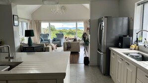 Une cuisine moderne dotée d’un grand îlot central, d’un réfrigérateur encastré et offrant une vue sur l’extérieur.