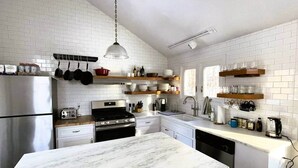 Una cucina moderna con pareti in mattoni bianchi, un piano di lavoro in marmo ed elettrodomestici in acciaio inossidabile.