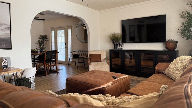 A living room with a fireplace, a TV mounted on the wall, and a dining area with a table and chairs.