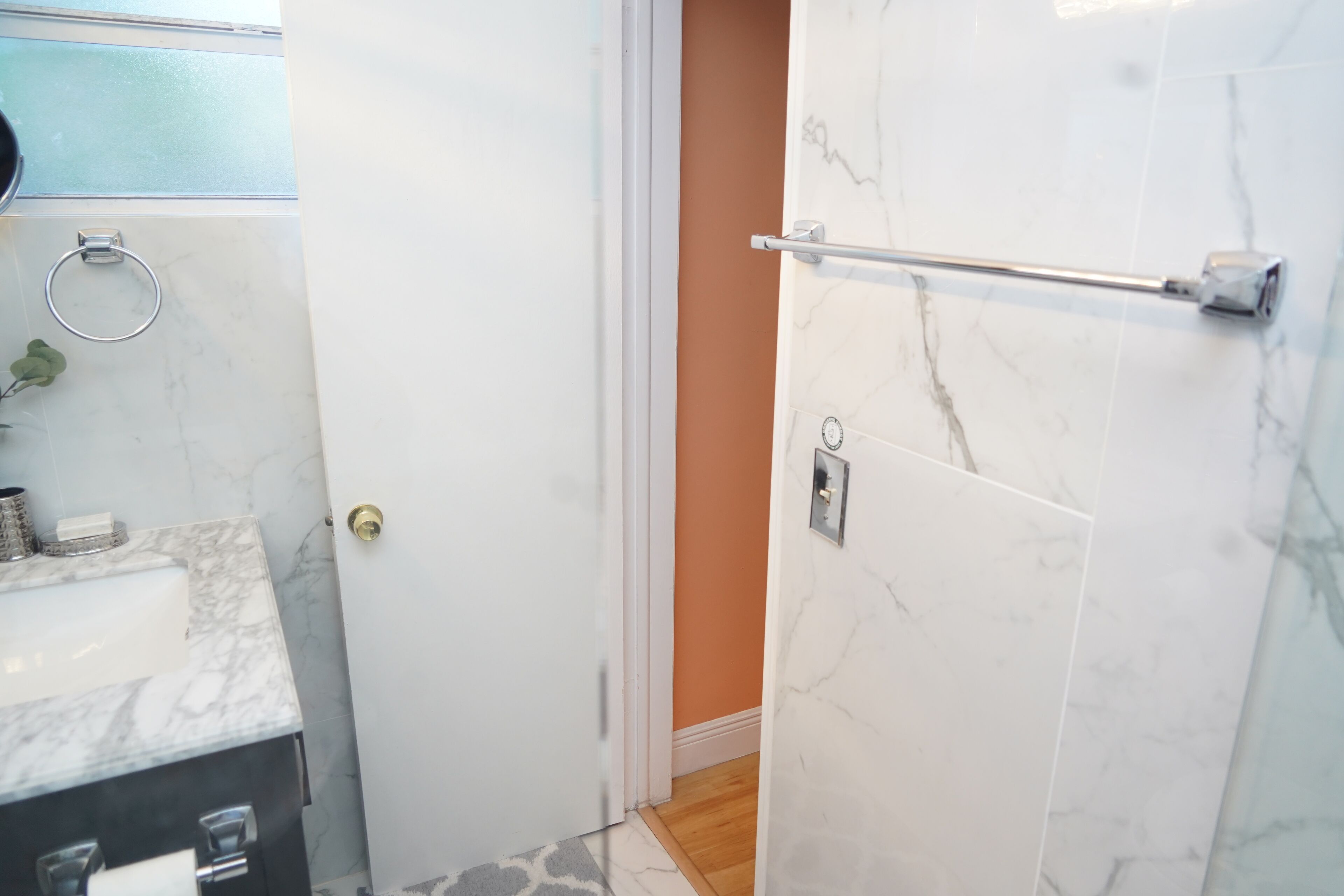 A bathroom with a marble sink, a towel rack, and a shower area with a glass door.