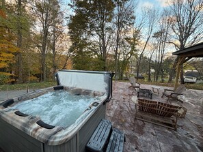 Un bain à remous doté d’une terrasse en bois et de mobilier d’extérieur, le tout entouré d’arbres.