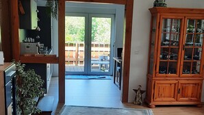 A spacious room with wooden flooring, a large cabinet with glass doors, and a view through a doorway to an outdoor patio area. - FeWo am Dachsberg, DTV certified with 3 stars (Kamp-Lintfort)