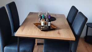 A dining area with a wooden table, four dark blue chairs, two glasses, and two bottles of liquor. - FeWo am Dachsberg, DTV certified with 3 stars (Kamp-Lintfort)