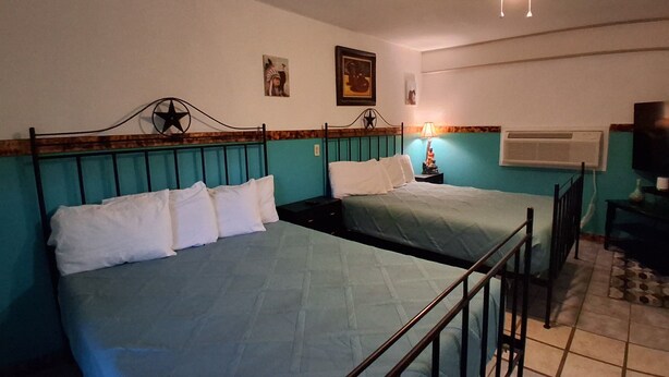 Une chambre avec deux lits, un ventilateur de plafond, un climatiseur mural et un téléviseur.