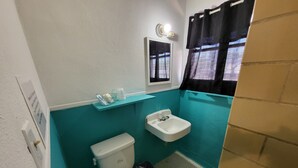 Une petite salle de bain comprenant des toilettes, un lavabo et une étagère avec des articles de toilette.