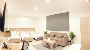 Una habitación de hotel moderna con una cama grande, un sofá, una mesa de centro, un escritorio con teléfono y una televisión.