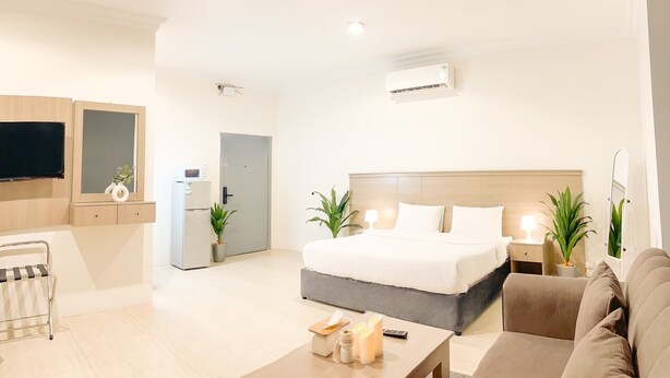 Una habitación de hotel moderna con cama, televisor, kitchenette y zona de estar.