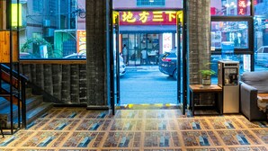 Entrada de hotel con piso estampado, una escalera y vista de la calle.