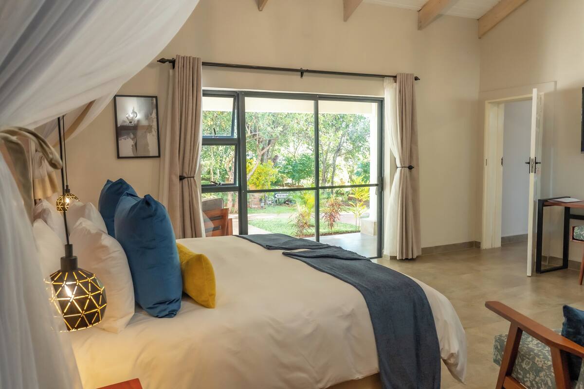 Quarto com uma cama grande, vista para o exterior e uma área de refeições.