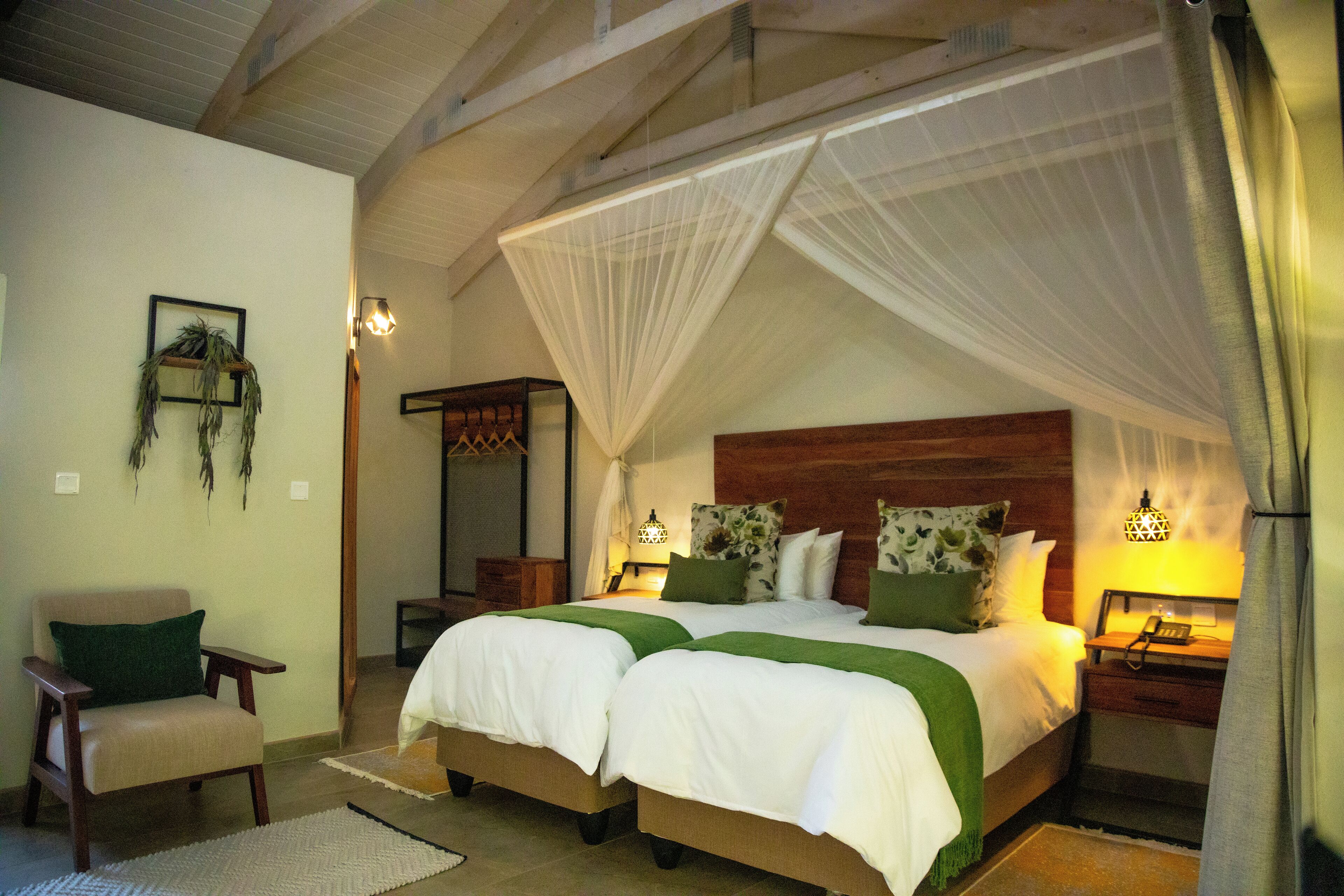A bedroom with two beds, a chair, a nightstand, and a bedside table.