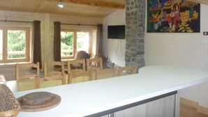 A spacious kitchen with a long counter, wooden chairs, and a stone accent wall. - Wifi, 300m from ski slopes, 2nd floor, tv, 87m², Les Gets (Les Gets)