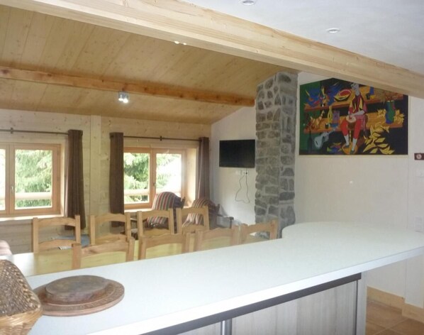 A spacious kitchen with a long counter, wooden chairs, and a stone accent wall.