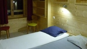 A wooden cabin room with a single bed, a chair, a small table, and a window with curtains. - Wifi, 300m from ski slopes, 2nd floor, tv, 87m², Les Gets (Les Gets)
