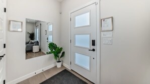 A hallway with a white door, a potted plant, and a framed certificate on the wall. - New house to stay in Calgary close to Airport and the big mall Crossiron Mill (Calgary)