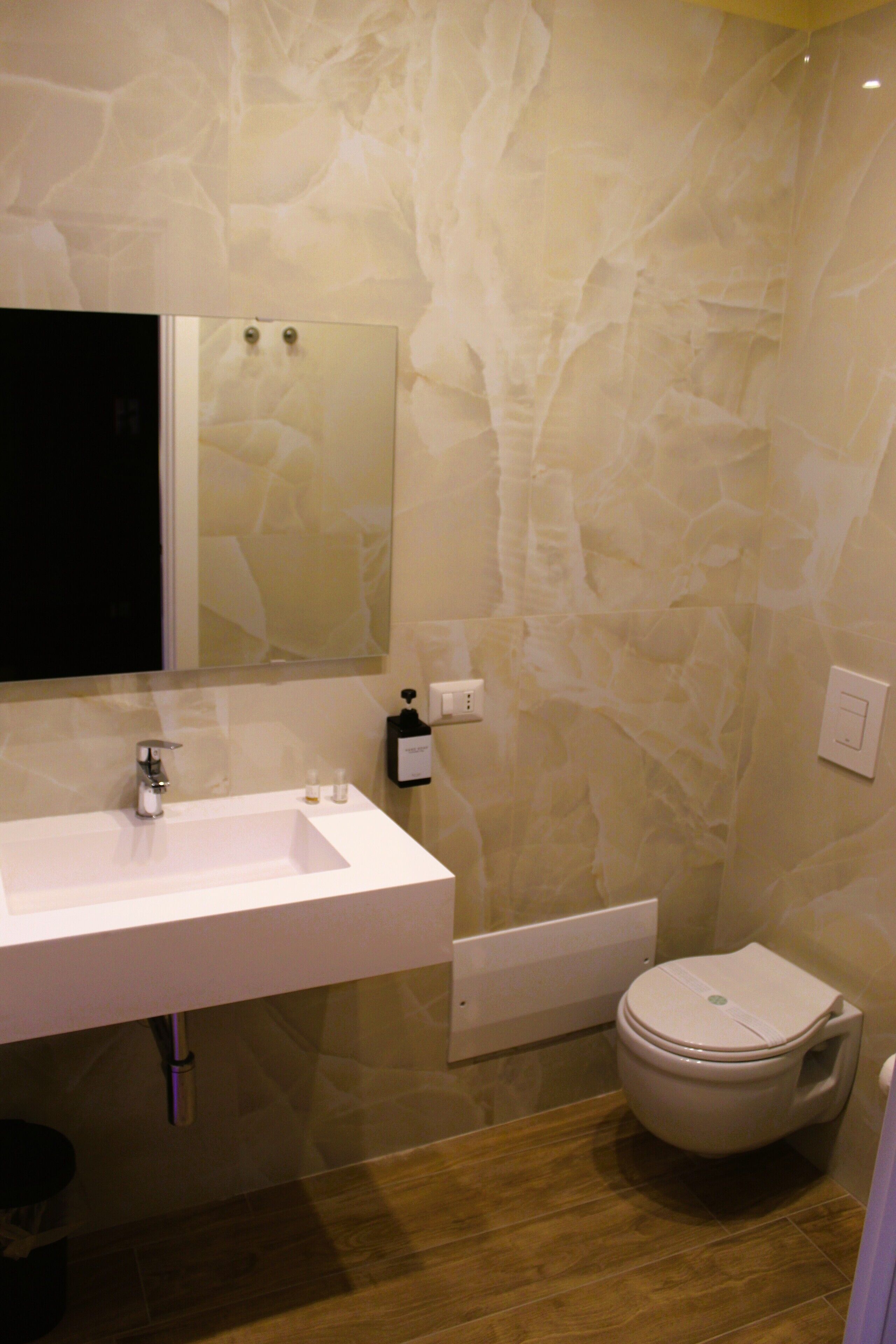 Un baño con lavamanos blanco, espejo e inodoro.