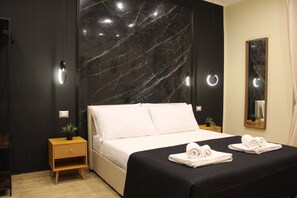 Une chambre d’hôtel moderne avec un grand lit, une table de chevet agrémentée d’une plante et un miroir au mur.