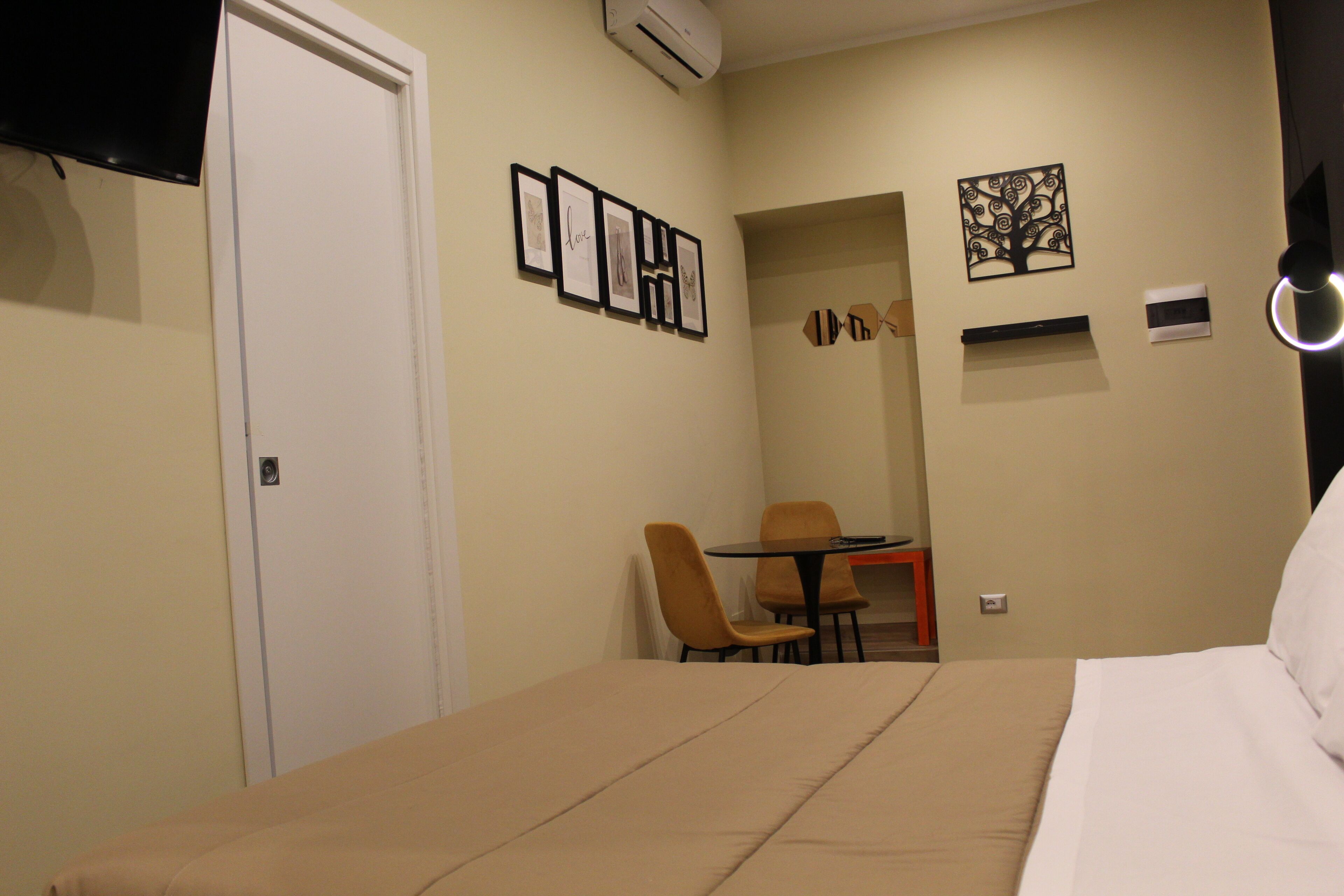 A hotel room with a bed, a desk with two chairs, and wall-mounted artwork.