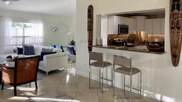 A modern living room with a sofa, chairs, and a dining area with a bar. - House - Sleeps 6 - Hot Tub - Garden - Near Beach (Naples)