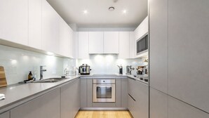 Una cucina moderna con mobili grigi, elettrodomestici in acciaio inossidabile e pavimento in legno.