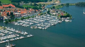 An aerial view of a marina with numerous boats docked, surrounded by residential buildings and a body of water.
