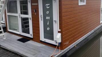 Een klein houten bootje met een witte deur waarop 'Tomo' staat en een raam.