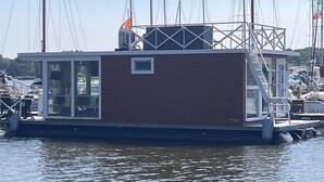 A floating houseboat docked at a marina with a clear sky.