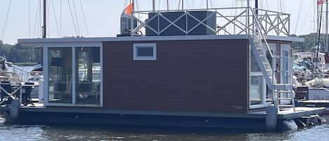 A floating houseboat docked at a marina with a clear sky.