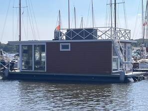 A floating houseboat docked at a marina with a clear sky.