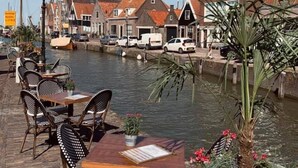 Cafetería a la orilla del río con terraza y vistas a edificios tradicionales.