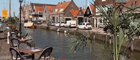 A riverside café with outdoor seating and a view of traditional buildings.
