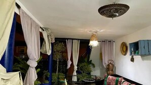 Una habitación con cama, lámpara colgante y ventana con cortinas.