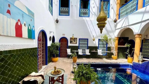 Un patio con piscina, suelo de baldosas y plantas en macetas.