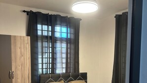 Un dormitorio con cama, armario, ventilador de techo y ventana con cortinas.
