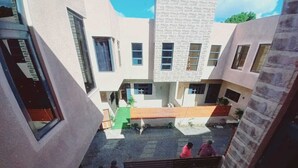 Un patio con un espacio abierto en el centro, rodeado de edificios con numerosas ventanas y una escalera que lleva a un nivel superior.