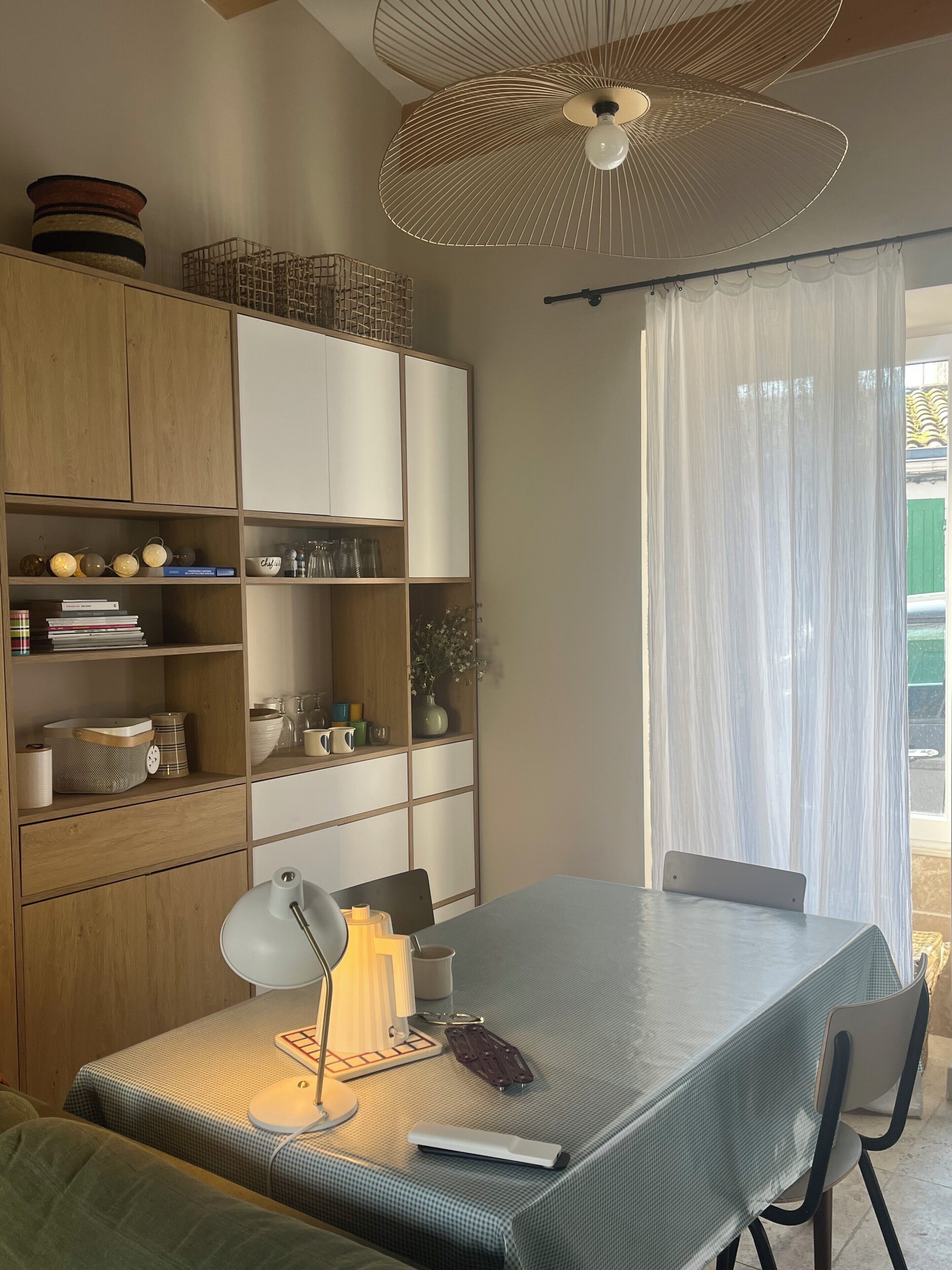 A modern room with a dining table, chairs, a lamp, and a ceiling fan.