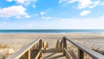 A wooden boardwalk leading to a beach with a clear sky.