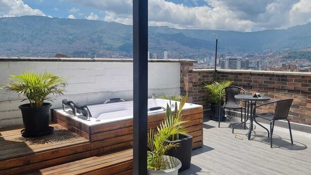 Eine Dachterrasse mit Whirlpool, Sitzgelegenheit und Blumentöpfen.