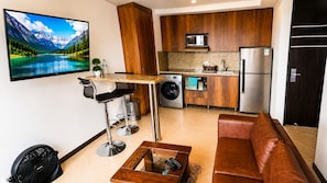Un espacio habitable compacto con cocina, zona de estar y televisor mostrando un paisaje montañoso.