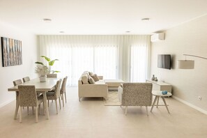 Una sala de estar moderna con una mesa de comedor, sofás, un televisor y una planta en maceta.