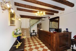 Un espace d’accueil avec un comptoir de réception en bois, un escalier et un lustre.